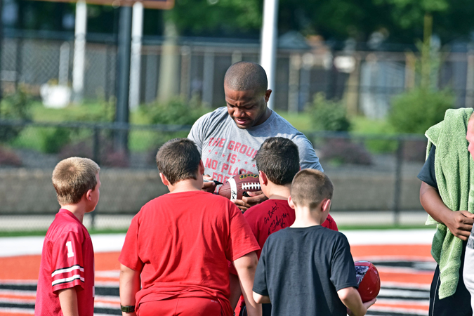 Former Ohio State running back Maurice Clarett autographs a football for a young fan during the 7-on-7 flag football game to benefit local police, firefighters and teachers. (Kent Sanborn of Southern Ohio Sports Photos.com)