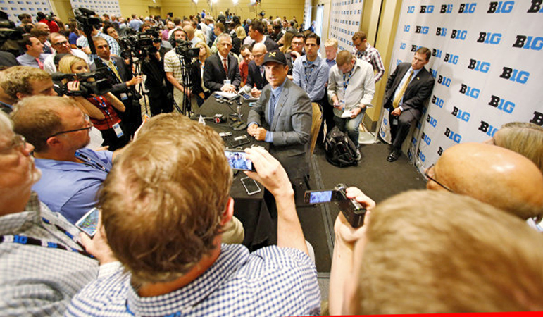 Michigan Wolverines head football coach Jim Harbaugh (seated) addresses the Big Ten media during the first day of the conference media days on Monday. (Photo Courtesy of Big Ten.com)